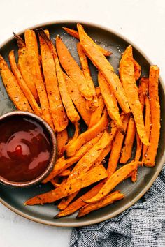 baked sweet potato wedges on a plate with ketchup and sauce in a bowl