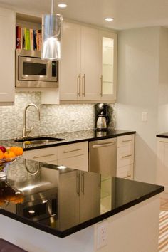 a modern kitchen with stainless steel appliances and black counter tops, along with white cabinets