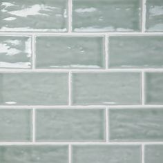 a close up view of a white brick wall with light green grouting on it