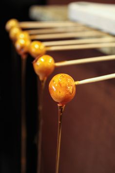 some yellow lollipops are lined up on a stick and ready to be eaten