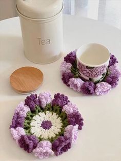 two crocheted coasters and a tea pot on a table