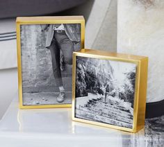 two black and white photos sitting on top of a table next to a vase with flowers