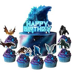 a birthday cake with cupcakes decorated like godzillas and monsters on it, surrounded by cut outs that say happy birthday