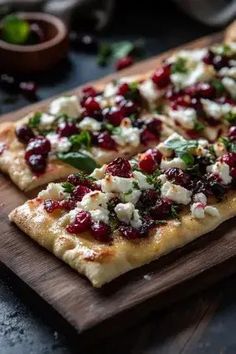 two flatbreads with cranberry sauce and cheese on a wooden cutting board