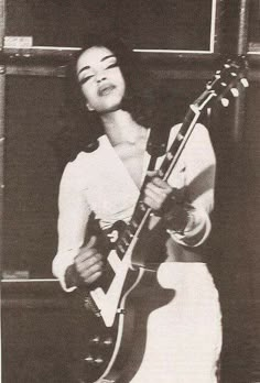 a woman holding an electric guitar in her right hand