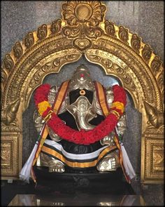 the statue is decorated with red and yellow garlands on it's headdress