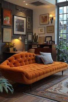 an orange couch sitting on top of a wooden floor in front of a large window