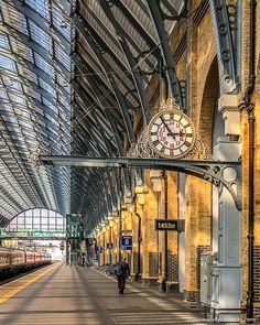 a train station with a clock on the wall and people walking in front of it