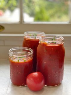 three jars filled with tomato sauce sitting on top of a counter