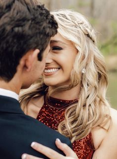 a man in a suit and tie hugging a blonde haired woman with her eyes closed