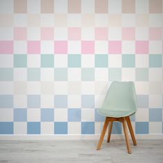 a chair sitting on top of a wooden floor next to a wall covered in pastel squares