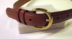 "Soft, quality chestnut brown leather strap with military-style brass hardware. Great choice for casual wear.  The sweetly cinched waist has classic styling and clean design. Definitely a basic staple of any fashion conscious wardrobe.   Generally very good condition. Leather unblemished. Small scratches on buckle underside from opening and closing hardly noticeable.   Gift yourself or a friend.   Measures: Total length 36'; width 1\". Buckle to first hole 32\"; to last hole 28\"." Casual Brown Belt With Buckle Closure, Classic Brown Belt With Brass Hardware, Brown Belts With Brass Buckle For Everyday, Brown Belt With Brass Buckle For Everyday, Brown Belt With Brass Hardware For Everyday, Vintage Brown Belt For Everyday, Casual Brown Belt With Brass Buckle, Classic Brown Belts For Fall, Casual Brown Belt For Workwear