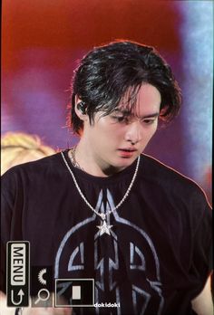 the young man is wearing a black t - shirt and silver chain around his neck