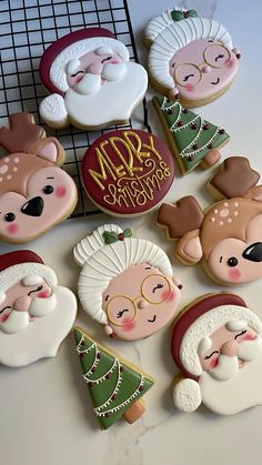 christmas cookies decorated with santa claus and other holiday related items are on a cooling rack