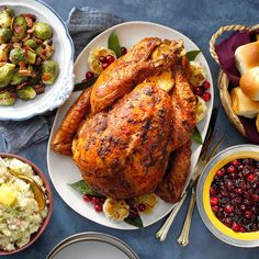 a table topped with plates and bowls filled with turkey, brussel sprouts, brussels sprouts, cranberry sauce