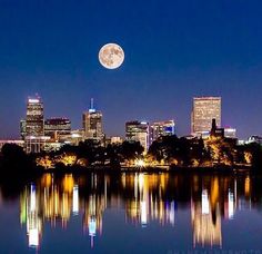 a full moon is seen over the city skyline in this photo taken from sloan's lake park