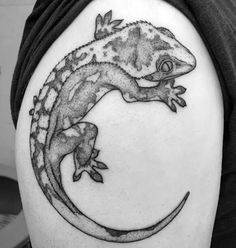 a lizard tattoo on the back of a man's arm, with its tail curled up