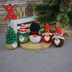 small crocheted christmas gnomes sitting on a wooden bench in front of a tree