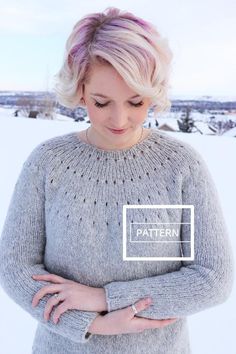 a woman standing in the snow with her hands on her hips and wearing a sweater that says pattern