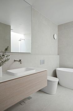 a bathroom with a large white tub next to a toilet and sink in front of a mirror