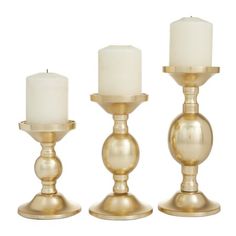 three gold candlesticks with white candles in them