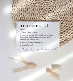 a bridesmaid card sitting on top of a table next to a straw hat