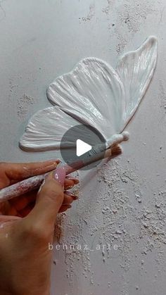 a person is painting the ceiling with white paint and a butterfly shaped object on it