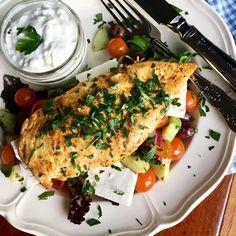 a white plate topped with fish and vegetables next to a bowl of yogurt