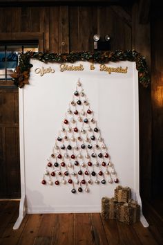 a christmas tree made out of wine glasses is displayed on a white board in front of a wood paneled wall