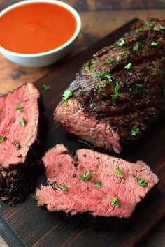 the steak is sliced up and ready to be served on the table with sauces