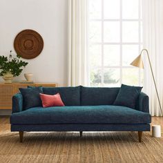 a living room scene with focus on the blue couch and rug, along with a large window