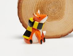 an orange and black figurine sitting on top of a piece of wood