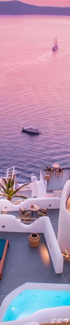 an outdoor hot tub next to the ocean at sunset with a boat in the distance