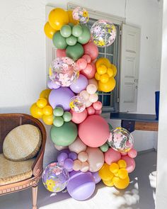 a bunch of balloons that are in the shape of a pyramid on a table next to a wicker chair