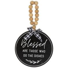 a wooden beaded necklace with a black and white sign that says, blessed are those who do the dishes