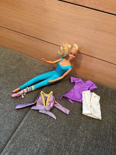 a barbie doll laying on top of a couch next to clothes