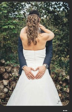 a bride and groom standing next to each other with their hands in the shape of a heart