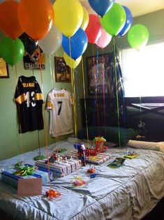 a bed topped with lots of balloons next to a table filled with gifts and presents