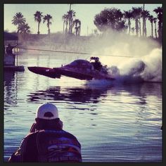 a man watching a boat crash in the water with palm trees behind him on a sunny day