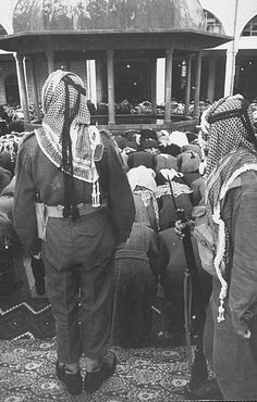 an old photo of some people standing in front of a building with many bags on the ground