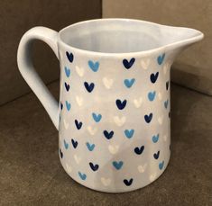 a white pitcher with blue hearts painted on it