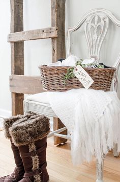 a white bench with a basket and boots on it, next to a wooden chair