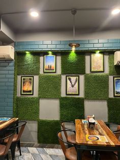 a green wall in a restaurant with pictures on the walls and chairs at tables around it