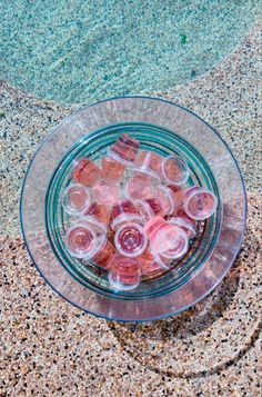 a glass bowl filled with water sitting on top of a sandy beach