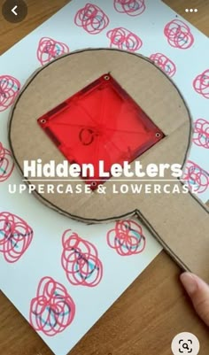 a hand is holding a red object over a piece of paper with circles and letters on it