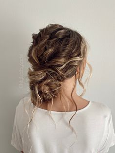 a woman with her hair in a low bun is shown from the back, wearing a white t - shirt