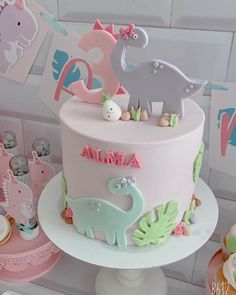 there is a pink and blue cake with animals on the top, along with other decorations