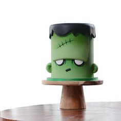 a cake that looks like the head of a zombie on top of a wooden stand