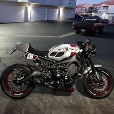 a motorcycle parked in a parking lot next to a black and white car at night