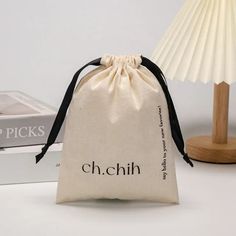 a small bag sitting on top of a table next to a lamp and some books